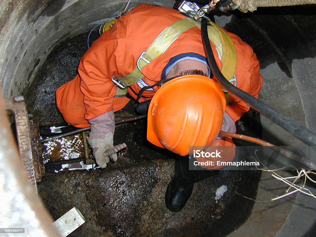 Manhole Man   Man in orange suit and hardhat in sewer.      Manhole Stock Photo