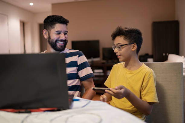 istock Father and son playing video game with smart phone and laptop 1404569592