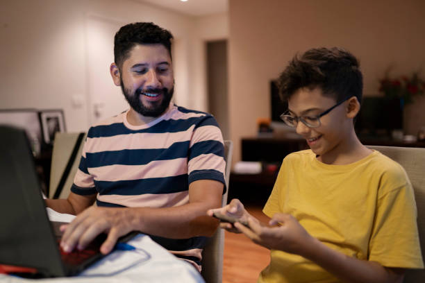istock Father and son playing video game with smart phone and laptop 1404569599