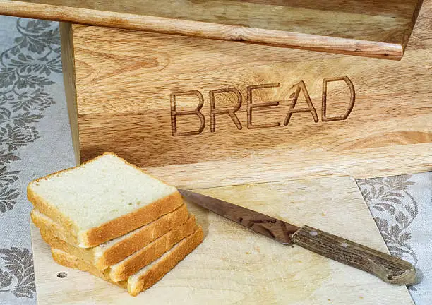 Bread, wooden bread-basket, knife, table-cloth. Country style.