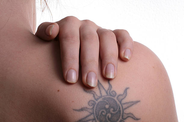 Person grabbing shoulder with tattoo to massage pain  stock photo