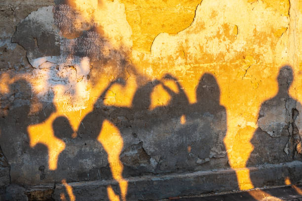 istock Shadows of dancing people on an old stone wall at sunset time. 1404573117