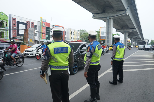 Makassar, Indonesia - June 13 2022: Indonesian police officers are controlling traffic flow on the highway