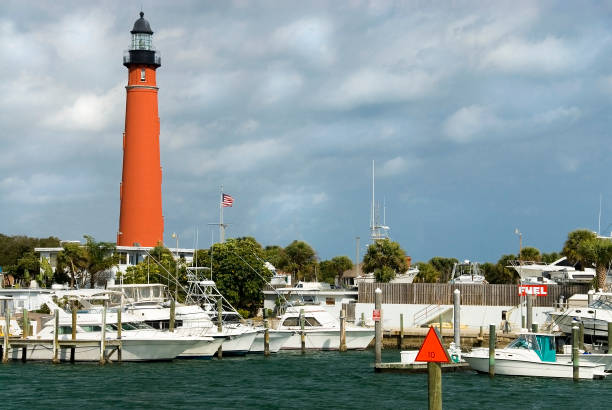 Lighthouse Marina A lighthouse guides to a safe harbor in this inlet harbor marina channel marker stock pictures, royalty-free photos & images