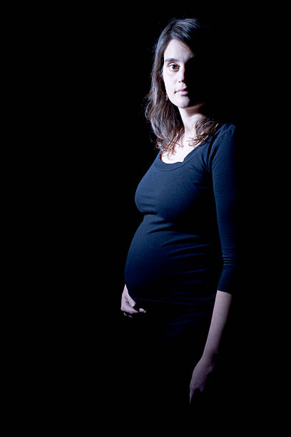 Donna incinta isolato con sfondo nero e snoot luce - foto stock
