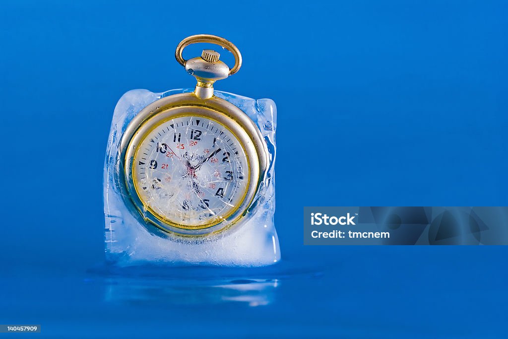 Frozen in Time 3 Pocket watch breaking free from a block of ice. The clock face is clearly visible through the cracked and broken ice. Image three in a series of three. Free time. Concepts Stock Photo