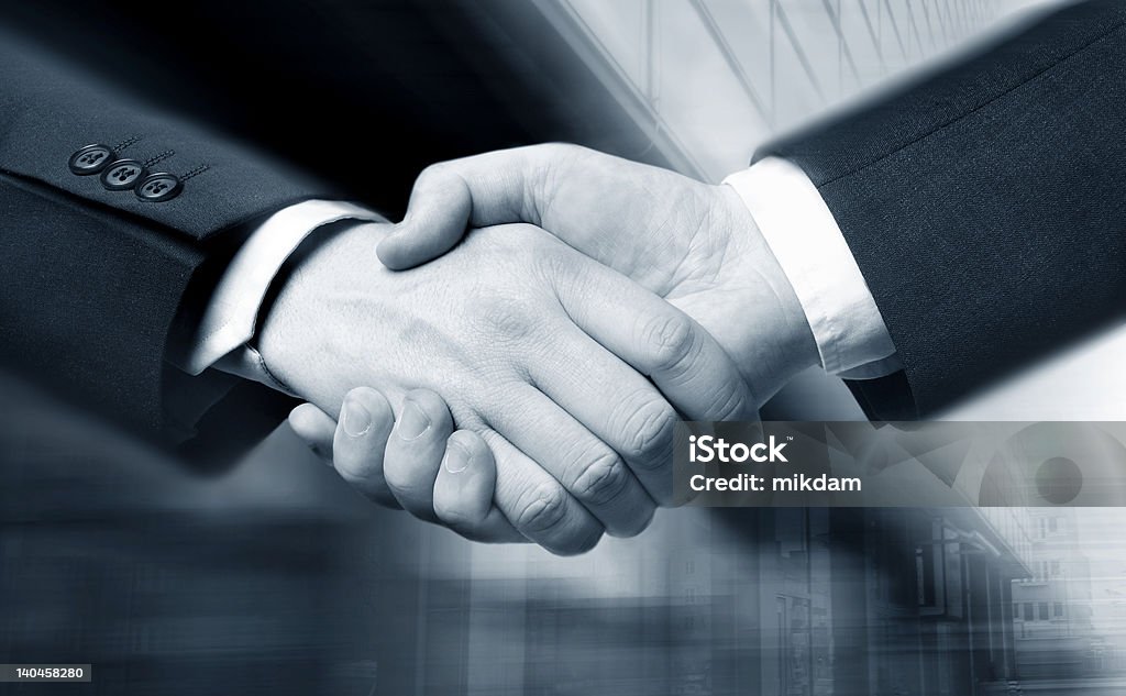 Professional business handshake in an office business hand shake and a office in background,  Suit slightly motion blur, focus at the hands Achievement Stock Photo