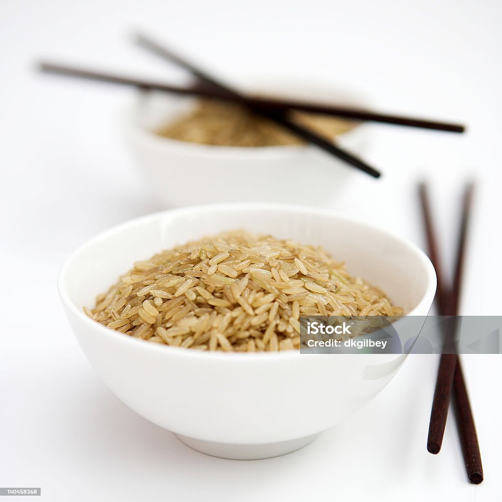 Brown rice Bowls of uncooked brown rice & chopsticks - shallow dof Bowl Stock Photo