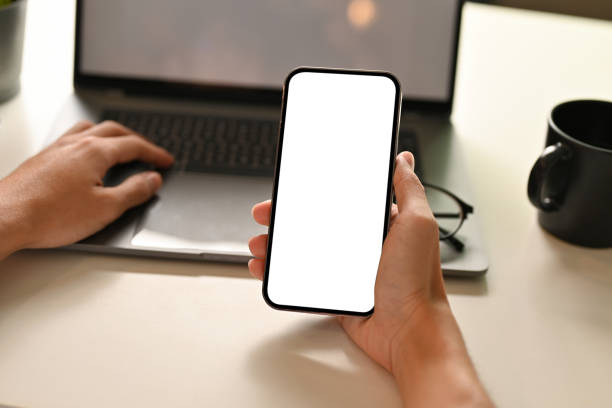 istock A businessman or man hands holding a smartphone white screen and using laptop 1404586749