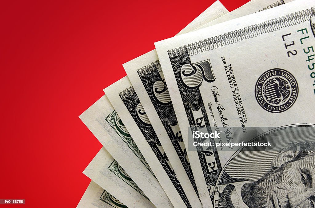Money on Red Background Closeup of five dollar bills against red gradient background. Banking Stock Photo