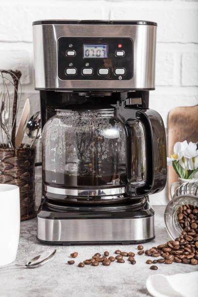 istock Drip coffee maker and white cup. Preparing hot coffee in a coffee machine. Household appliances on the kitchen table 1404591355