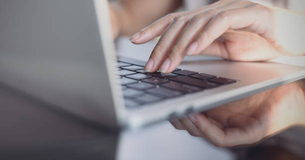 istock Woman hands typing on laptop computer keyboard on glass table, close up 1404593313