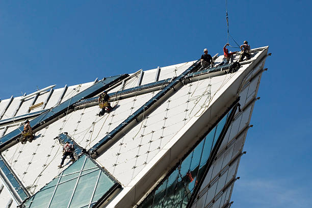 Construction workers on steep roof stock photo