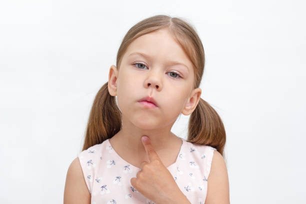 Child pointing at throat by index finger showing voiceless and speechless Portrait of caucasian little girl of 6 years pointing at throat by index finger showing voiceless and speechless. Concept dysarthria, logopedics pain points stock pictures, royalty-free photos & images