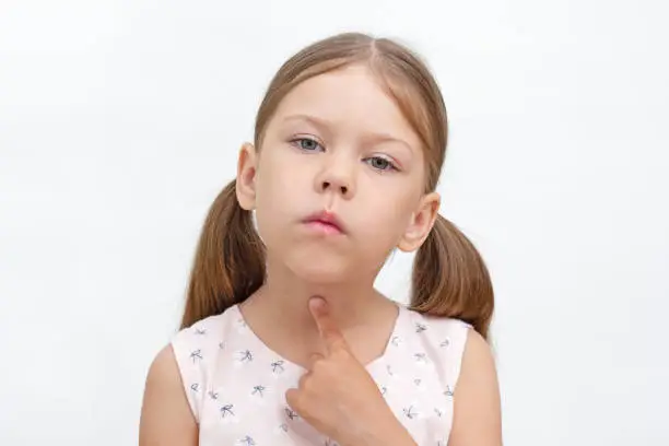 Photo of Child pointing at throat by index finger showing voiceless and speechless