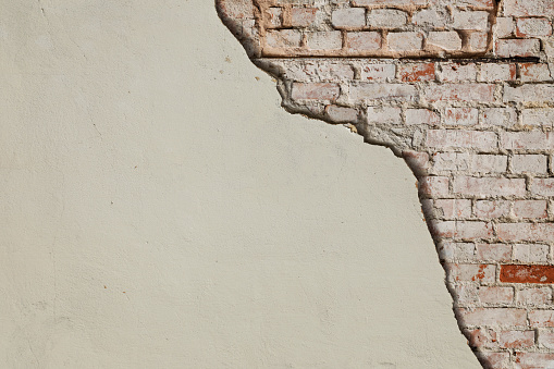 Red brick wall under the damaged concrete wall