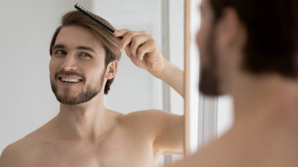 istock Happy young handsome man styling hair with comb. 1404603905