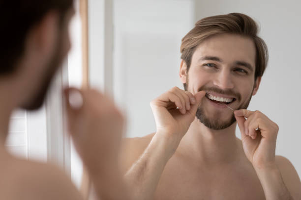 istock Happy millennial man cleaning teeth with dental floss. 1404603909