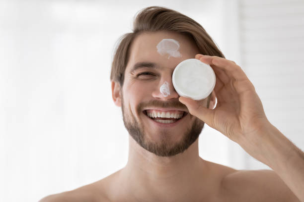 istock Happy young handsome man applying moisturizing cream. 1404603916