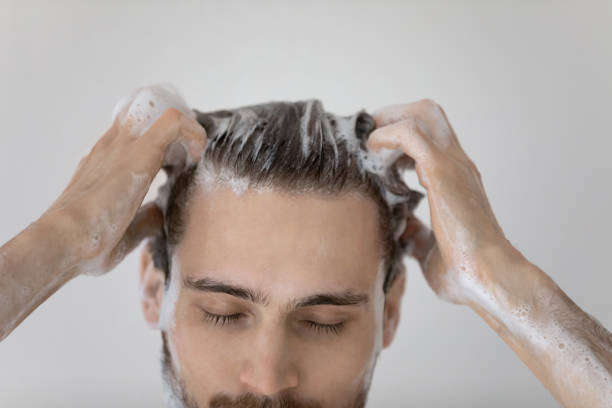 Close up young european man washing hair in shower. Close up young european man washing hair with anti-dandruff foamy natural shampoo, peeling head skin in bathroom, enjoying morning showering body cleaning routine, personal daily hygiene concept. dandruff stock pictures, royalty-free photos & images