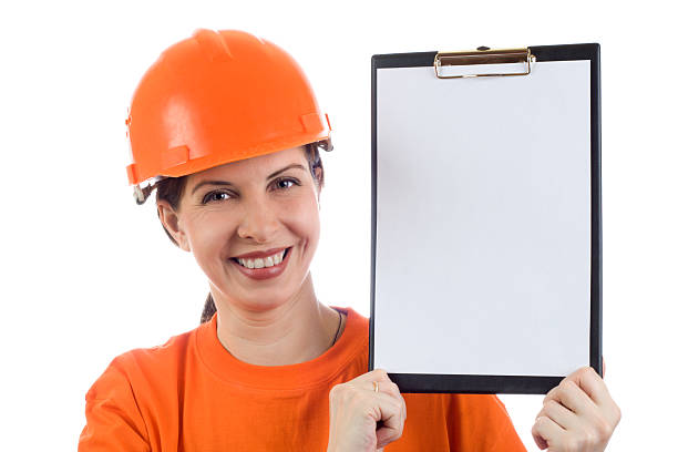 Young woman in orange safety helmet shows the blank page stock photo