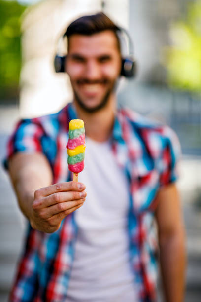 istock Young man eating ice cream outdoors. 1404607313