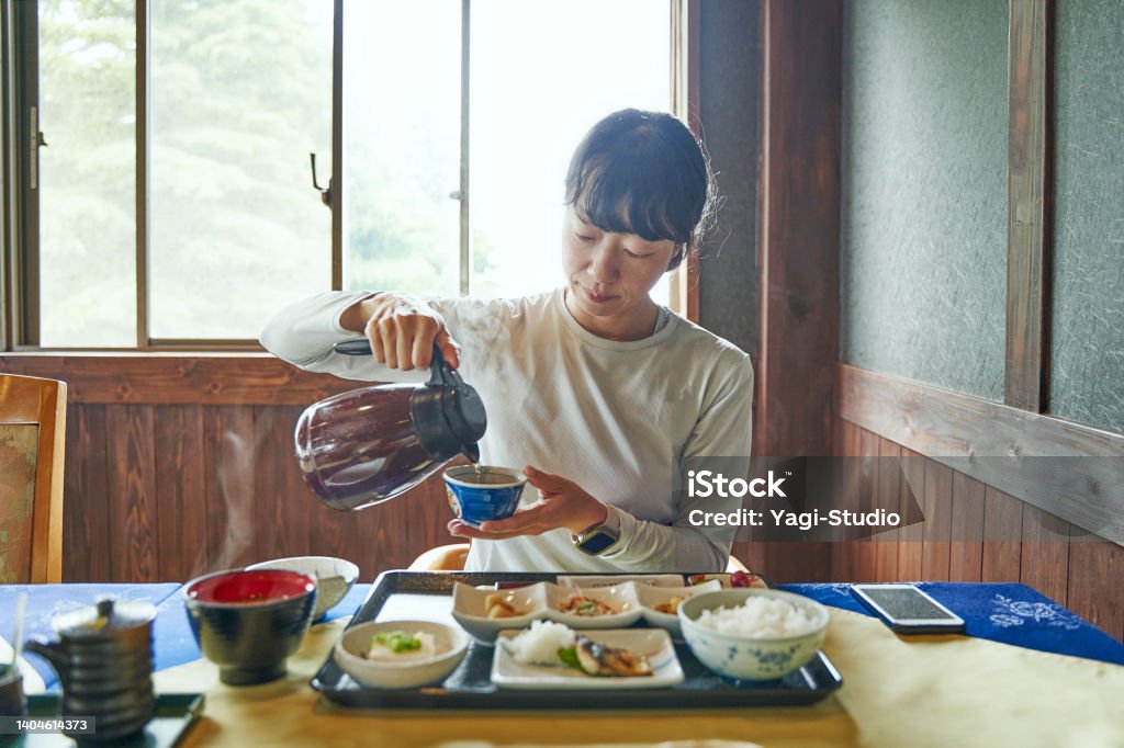 Woman staying at a mountain lodge eats a Japanese-style breakfast before setting off to climb a mountain. Japanese woman walk on a hiking trail called the Diamond Trail. The Diamond Trail is a long-distance nature trail that traverses the ridges of the Kongo-Katsuragi mountain range. Breakfast Stock Photo