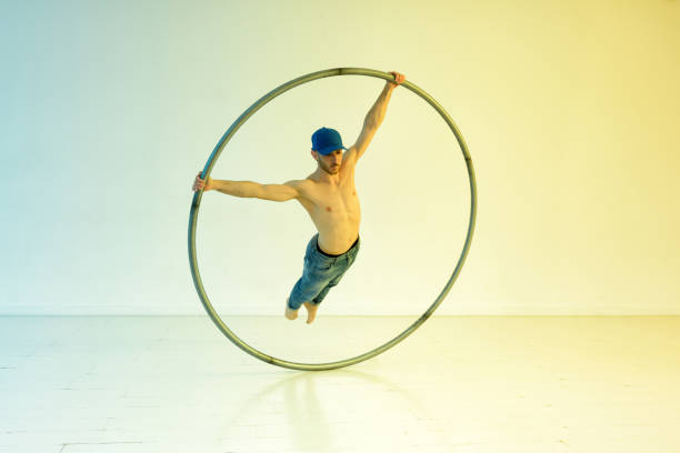 Acrobat training on a spinning cyr wheel performing a superman trick over a colorful graduated background with copyspace