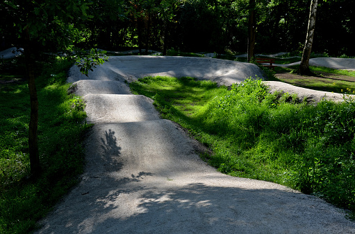 forest in which there is a track for bicycles trail tilted bends one after the other dug in the ground into perfect shapes mountain bikes even for children, glade, sun, shadows, racing  new, lawn, extension, pumptrack, pump track, tilted,