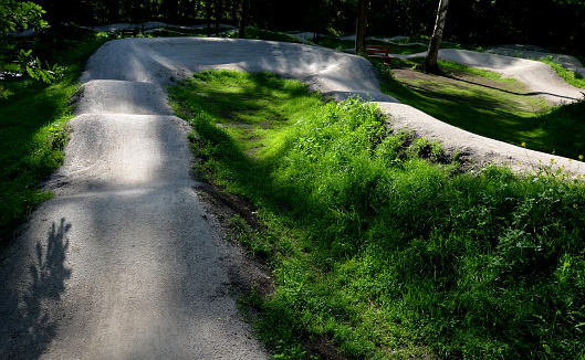 forest in which there is a track for bicycles trail tilted bends one after the other dug in the ground into perfect shapes mountain bikes even for children, glade, sun, shadows, racing  new, lawn, extension, pumptrack, pump track, tilted,