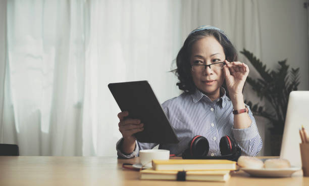 istock Smiling beautiful senior asian woman using digital tablet at home. work from home concept. 1404615409