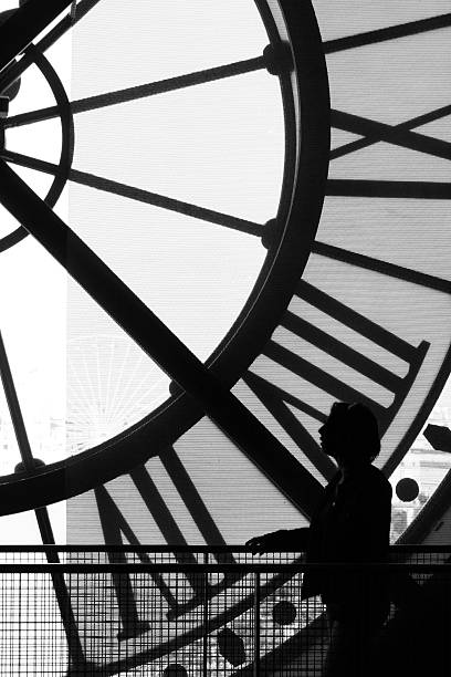 Ran Tempus Black and White scene where a model is seen looking at the street through a large clock. musee dorsay stock pictures, royalty-free photos & images