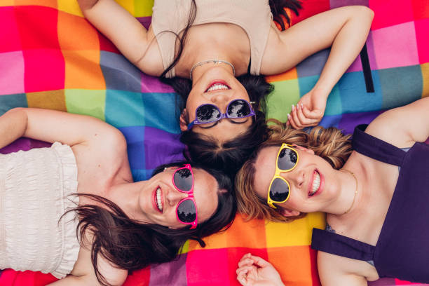 Happy diverse girlfriends lying on colorful blanket