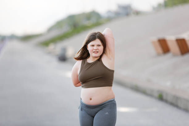 girl child teenager in sportswear with excess weight does exercises, plays sports outside in summer. - teen obesity imagens e fotografias de stock