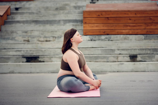 teenagerin mit übergewicht macht yogaübungen auf matte auf betonweg, promenade in der stadt - teen obesity stock-fotos und bilder