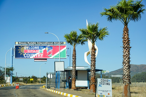 Hosea Kutako International Airport at Windhoek in Khomas Region, Namibia, with a billboard advert for SPAR and a security guard in the background as well as a monument.