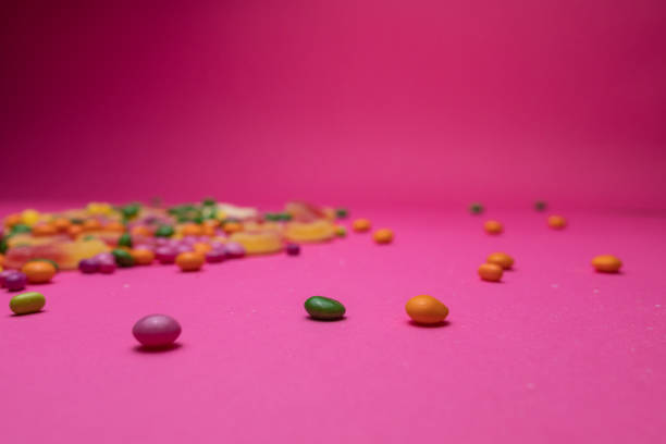 Close-up shot of various colorful candy on a bright pink background.