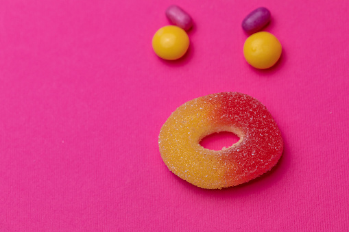 An angry facial expression created using an extreme close up shot of candies on a bright pink background.