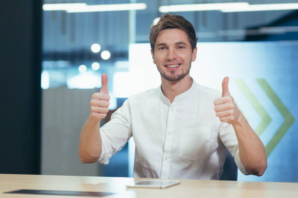 istock Man in modern office working, talking on video call looking at camera smiling showing thumbs up 1404622517