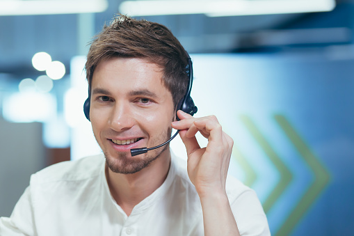 Close-up portrait of a man with a headset for a video call, looking at the camera and smiling employee technical support consultant