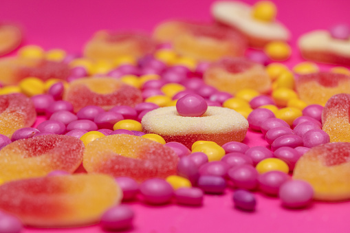Extreme close up shot of various candies and sweets on a bright pink background.