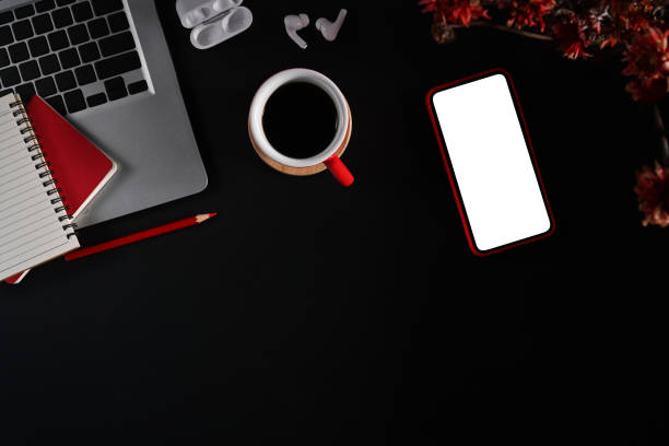 istock Modern workspace with smart phone, laptop, coffee cup and notepad on black background. Flat lay, top view. 1404622751