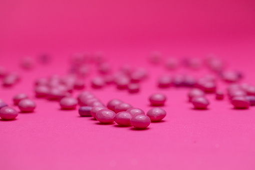 Close up of purple candies on a bright pink background.