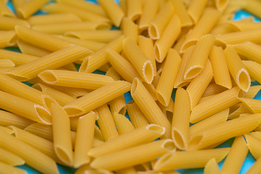 Close up of raw pasta on a blue background.