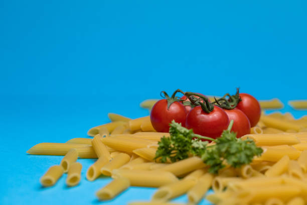 Stock photo shows an appetizing penna pasta dish features juicy cherry tomatoes, fresh basil leaves, creamy burrata cheese, and soft buffalo mozzarella. Artfully arranged, the ingredients showcase a perfect blend of color and texture, capturing the essence of traditional Italian cuisine