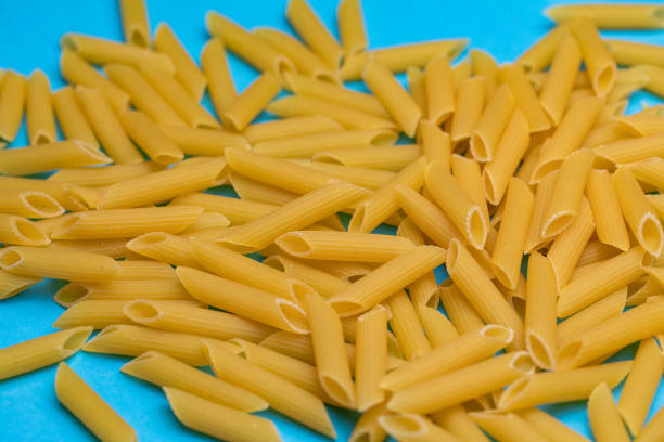 Raw pasta tubes on blue background