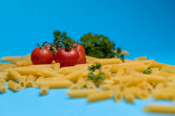 istock Raw pasta, cherry tomatoes and parsley on blue background. 1404624003
