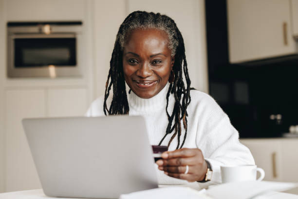 mulher feliz e madura fazendo compras online com um cartão de crédito - looking at camera senior women laptop only women - fotografias e filmes do acervo