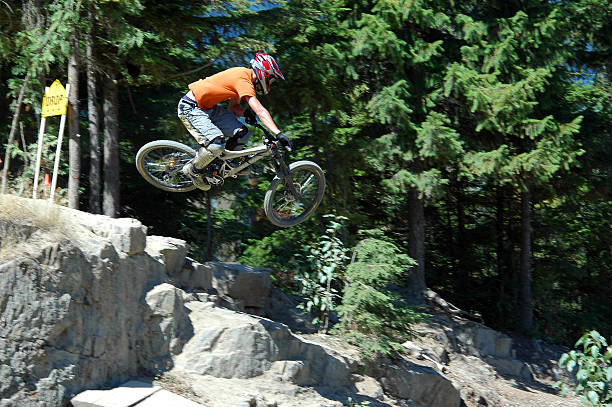 A mountain biker hits one of the GLC drops in Whistler, BC. He pushes the bike sideways as he launches of the drop.