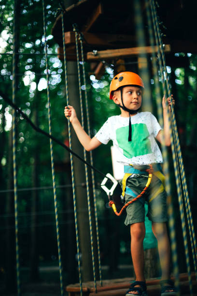 istock Cheerful boy in a helmet having fun in a rope park at sunset 1404627407